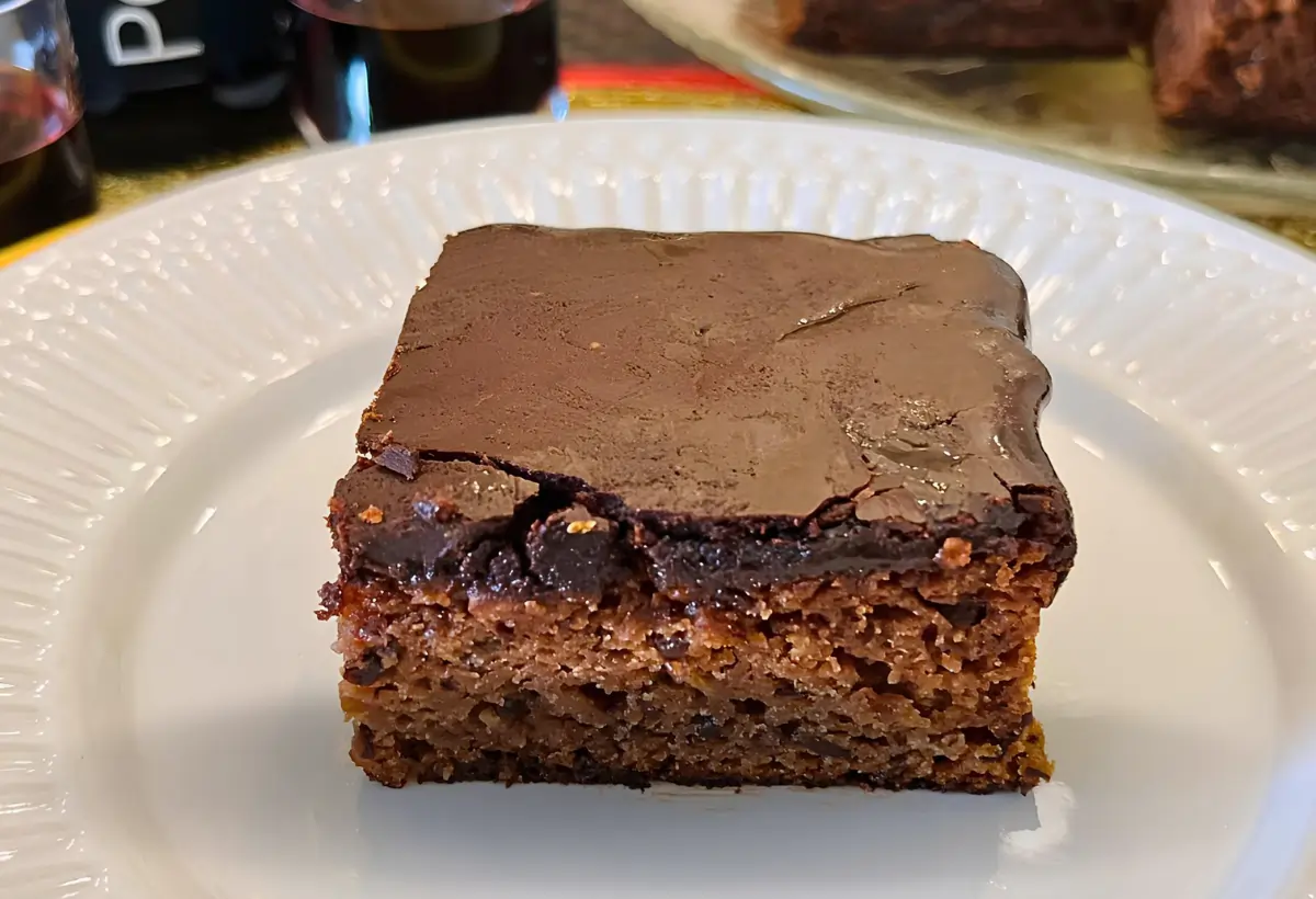 Um prato com uma fatia de bolo nega maluca com cobertura durinha.